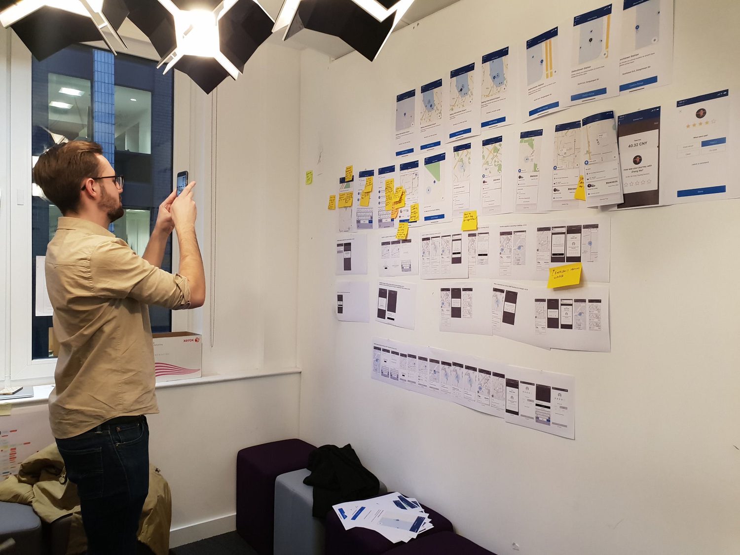 Designer photographing the native-app trip flow built out on the wall